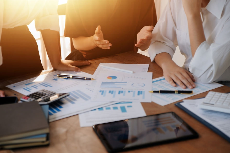 Business people meeting, discussing documents and charts on a wooden table.
