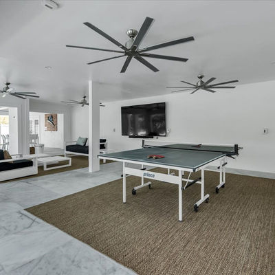 Ping pong table in a modern lounge area with ceiling fans.