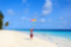 Child flying a colorful kite on a sunny beach