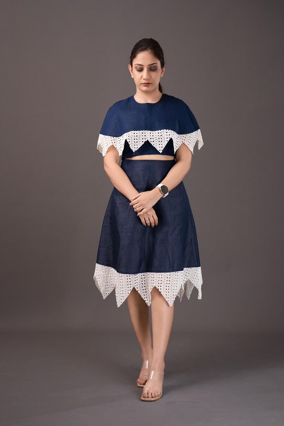Woman wearing blue cape top and skirt with white trim