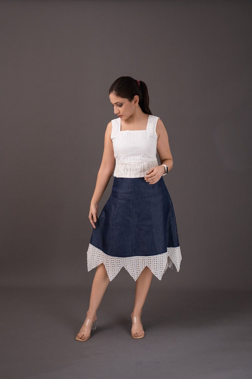 Woman in white sleeveless top and blue skirt with jagged hem