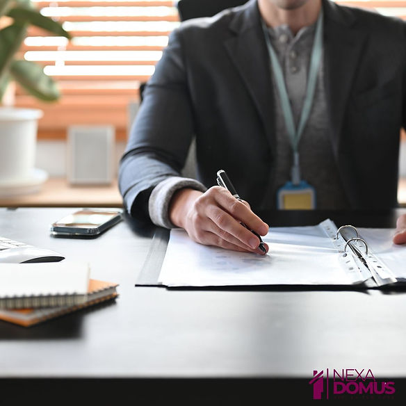 Uomo in ufficio mentre firma documenti su scrivania professionale.