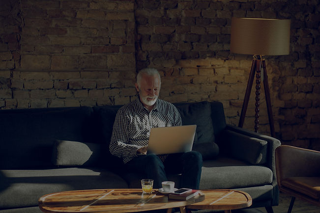 Elderly man on sofa working on laptop