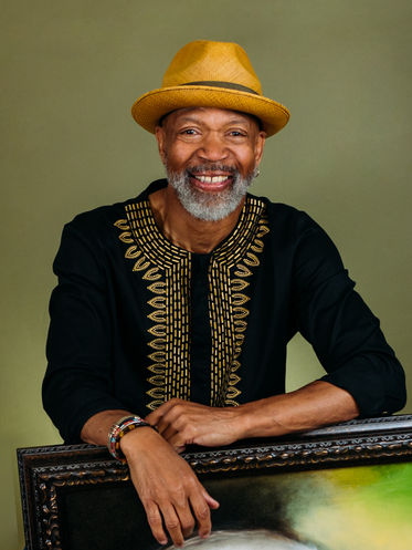 Headshot of man in hat with one of his paintings