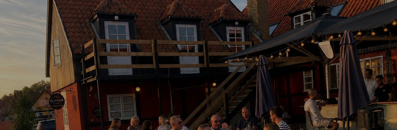 Gæster på terrassen ved Klippen Hotel – Skt. Jørgens Gaard og baren Jylkat i Gudhjem i aftensol
