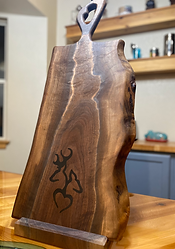 Black walnut cutting board with one long handle and engraved image of deer.