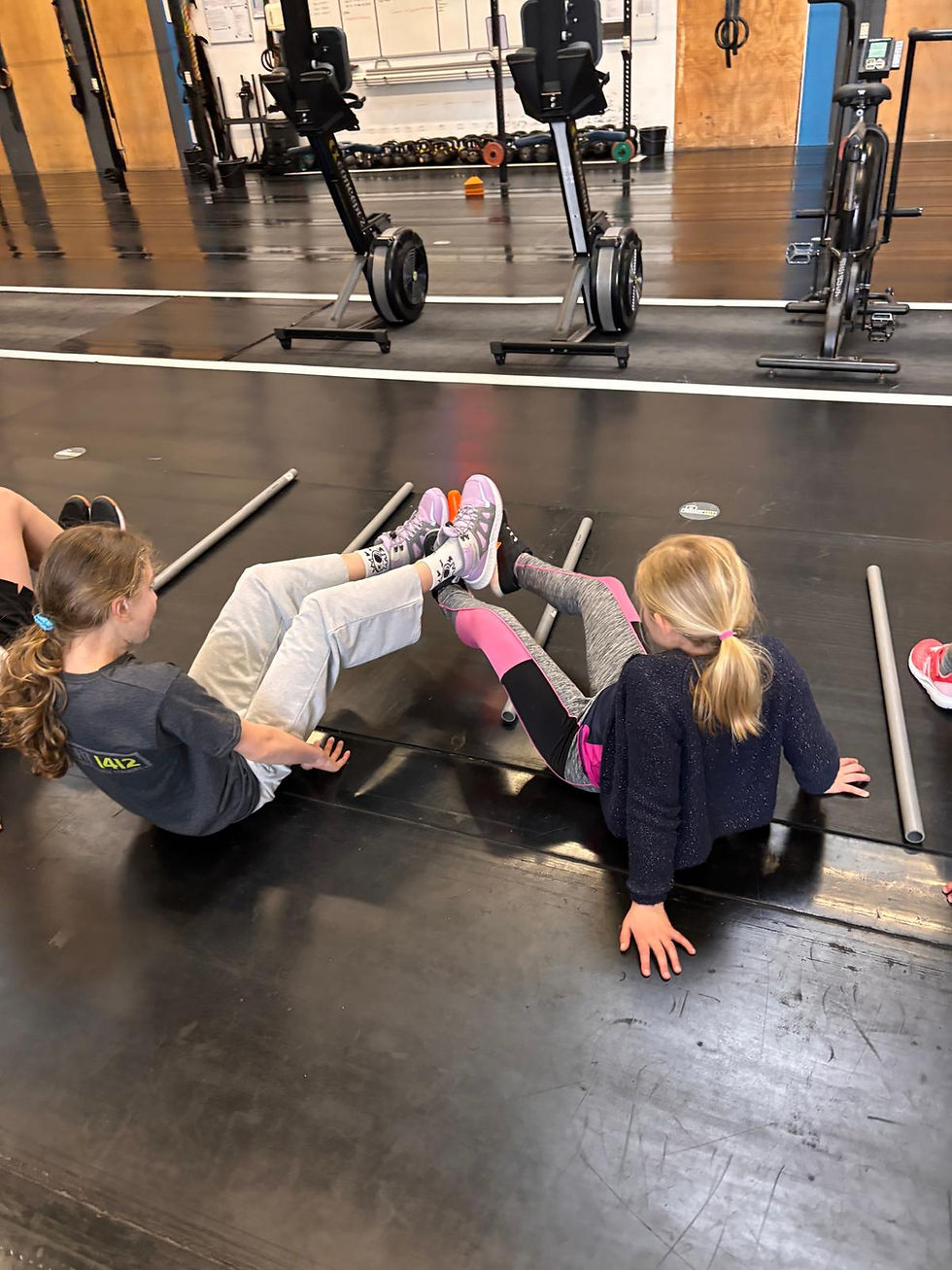 Kinderen doen oefeningen op de vloer tijdens CrossFit Kids