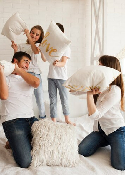 familia-juguetona-teniendo-pelea-almohadas-graciosa-cama_23-2148208005.jpg