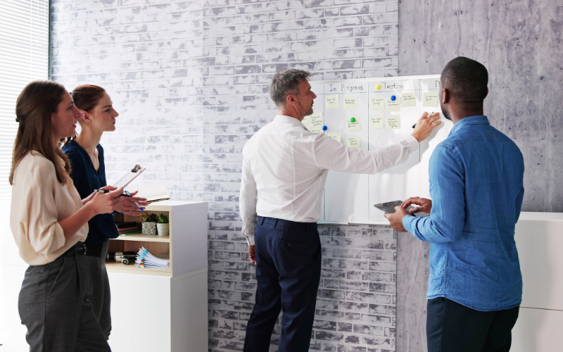 Close-up view of a project plan on a desk with sticky notes and a laptop