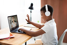 Primary school student attending an online tutoring session using a laptop and headphones