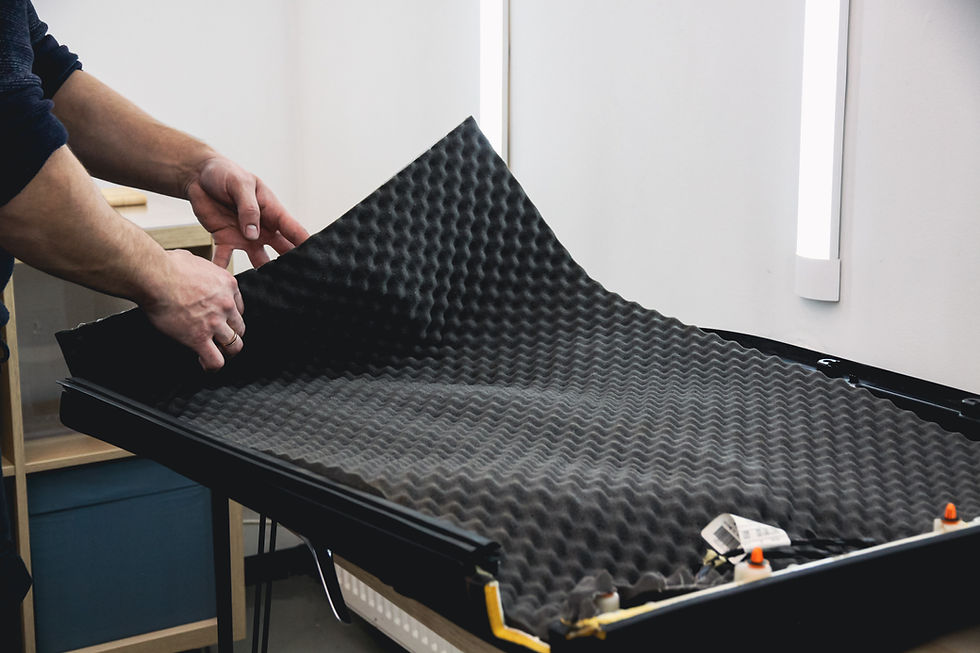 Cilvēks pieliek akustisko putu paneli uz galda gaišā telpā. Panelim ir melns viļņveida raksts.