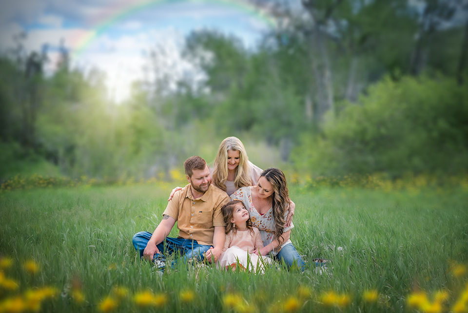 Parents and children sitting together in a grassy field during an outdoor family portrait session near Ogden, Utah