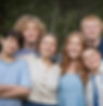 Family with older children smiling together in an outdoor portrait