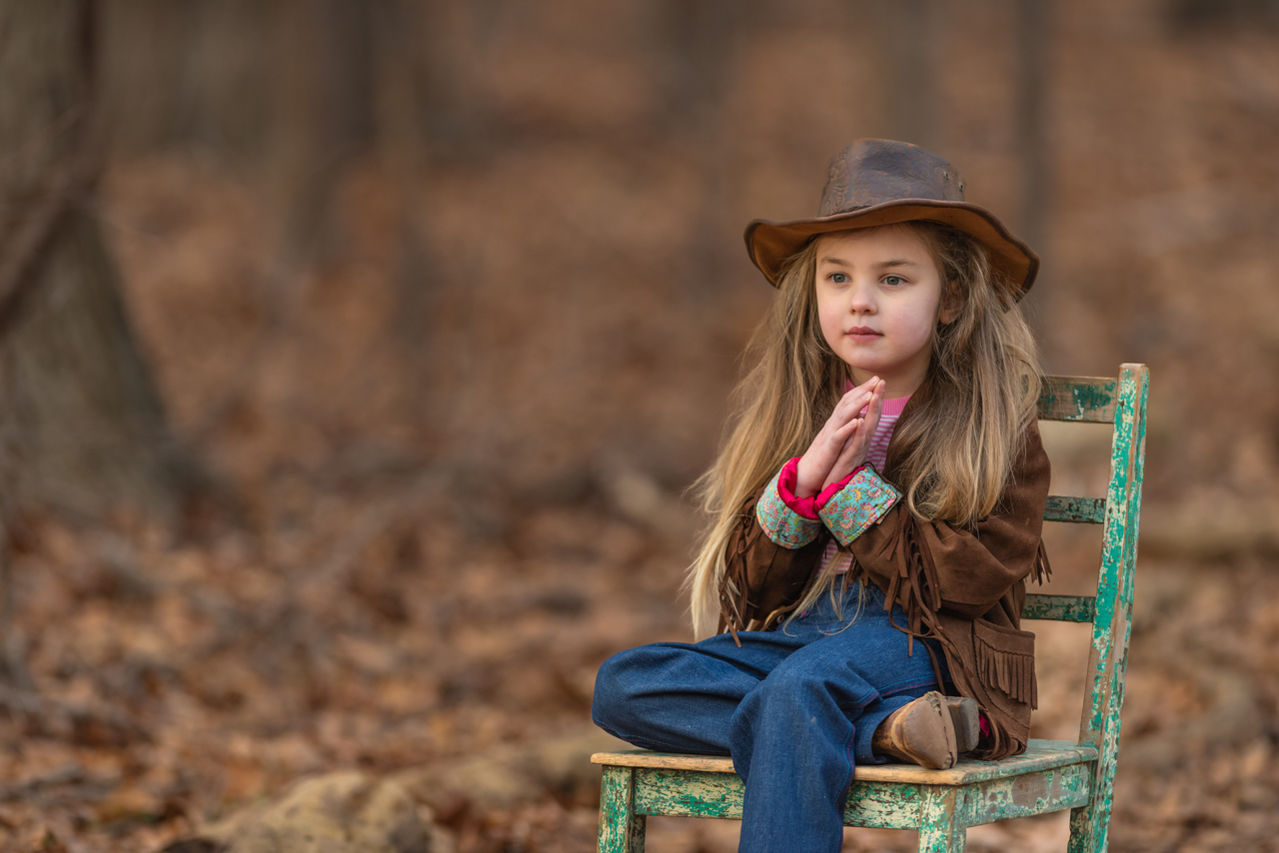 Young girl wearing a hat while seated outdoors during a portrait session near Ogden, Utah