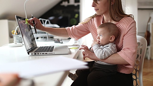 A woman working with a baby on her lap