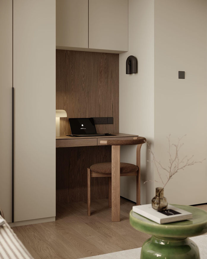 Compact home office space integrated into a wall niche, featuring a minimalist wooden desk, a laptop, and a wooden chair.