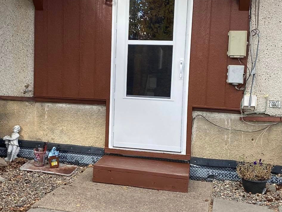 White entrance door with brown awning and steps