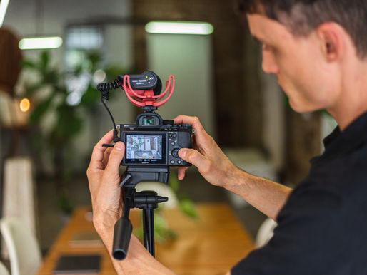 Videographer adjusting a camera with an external microphone on a tripod