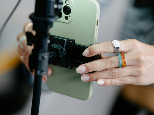 Person securing a smartphone to a stand below a ring light