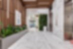 Modern lobby with marble floors, wood slat ceiling, plant wall, elevator, and signs reading 1 and Out of Order.
