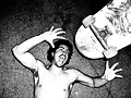 Black and white photo of a man screaming with a skateboard near his face.