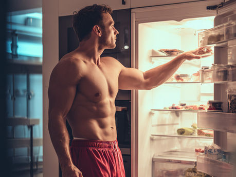 A healthy and fit man getting food out of a refrigerator