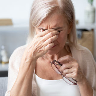 A woman holding her eyes to release pressure and pain that she fee;s as a result of glaucoma