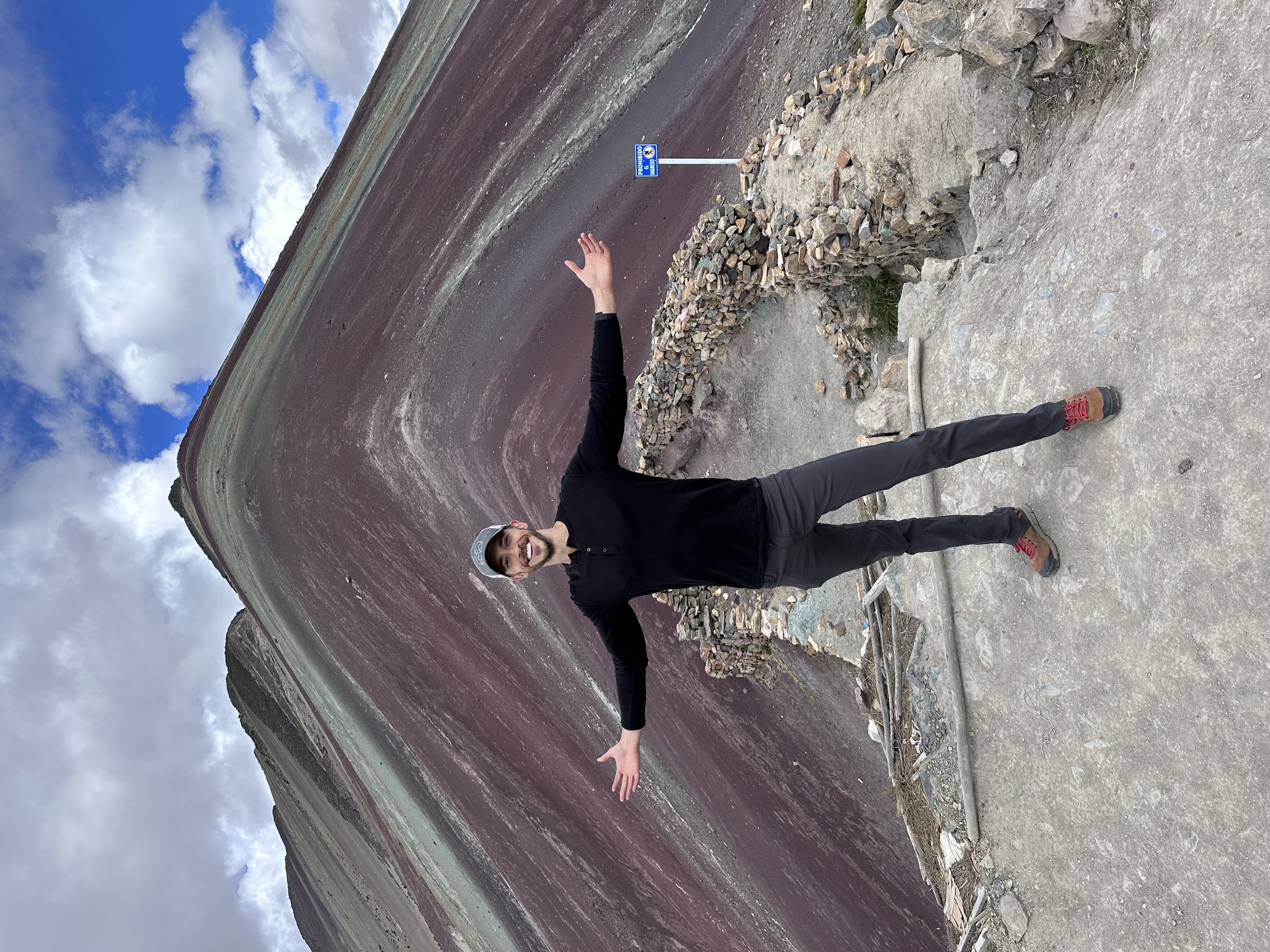 Danny Goldstein posing in front of Rainbow Mountain in Peru