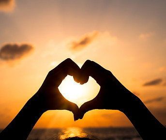 Hands forming a heart with a sunset in the background