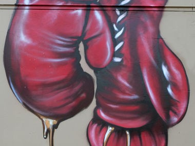 Boxing Gloves hanging spray painted on a wall. At least the gloves get padding in their fight.