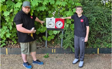 Bradley standing proudly next to the scoreboard showing his win with Coach Mark Bell