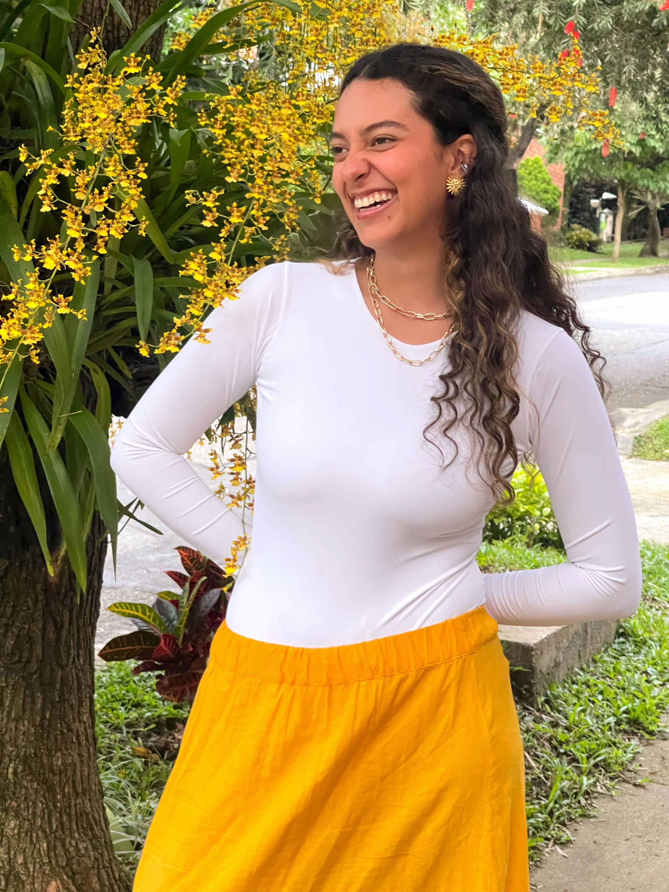 Modelo luciendo el body manga larga blanco Magnolia de dPAOL con falda amarilla. Outfit casual elegante.