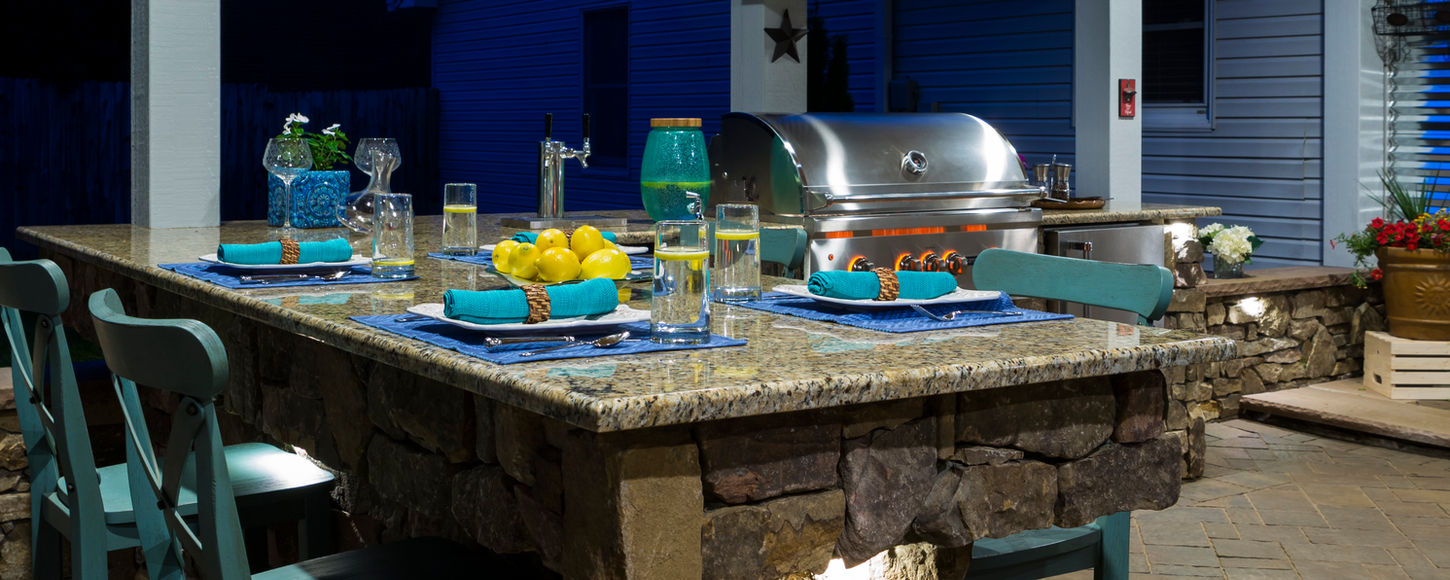 Natural stone outdoor kitchen with granite countertop and built-in appliances on a custom paver patio