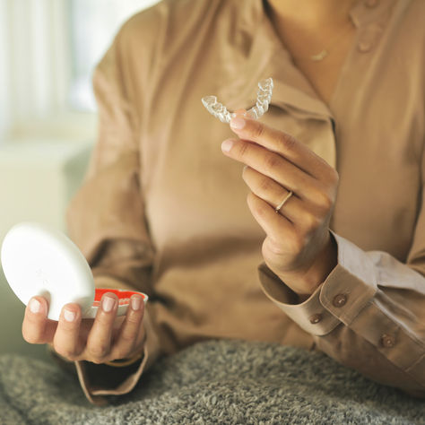 Mujer de blusa beige sacando los retenedores Vivera del estuche blanco