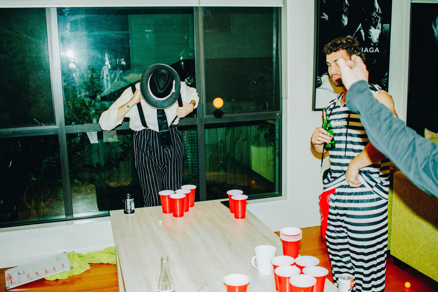 Men playing beer pong game with red cups at a party