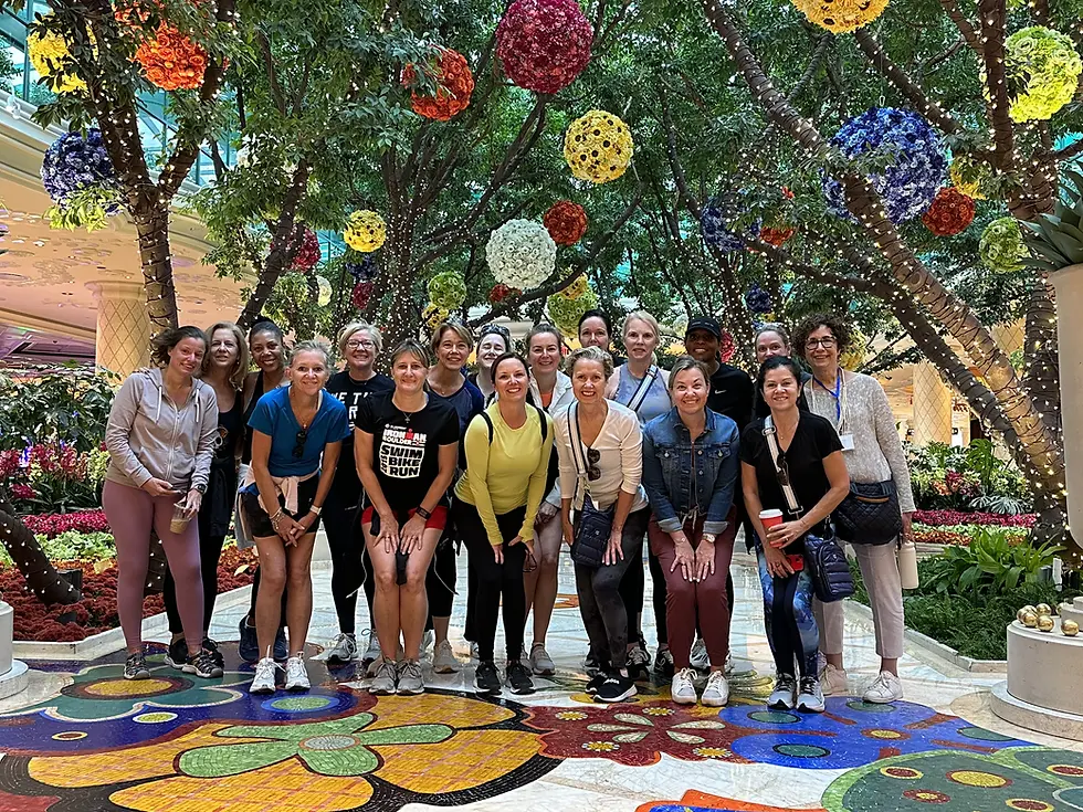 Group of women standing smiling amidst vibrant indoor garden decorations.