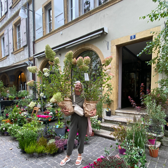 Femme souriante tenant des hydrangeas devant une jardinerie