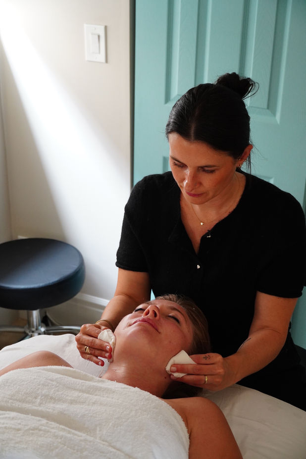 Facial treatment: Esthetician cleansing client's face