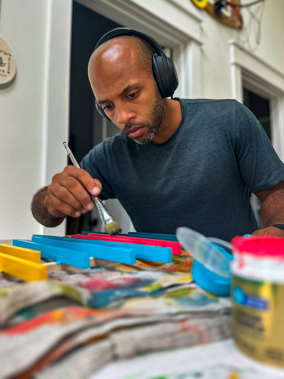 Juniro paints wooden blocks, wearing headphones, detailed view of art project Juniro Design