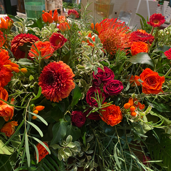 Gerberas, roses, et proteas orangées dans une composition florale.