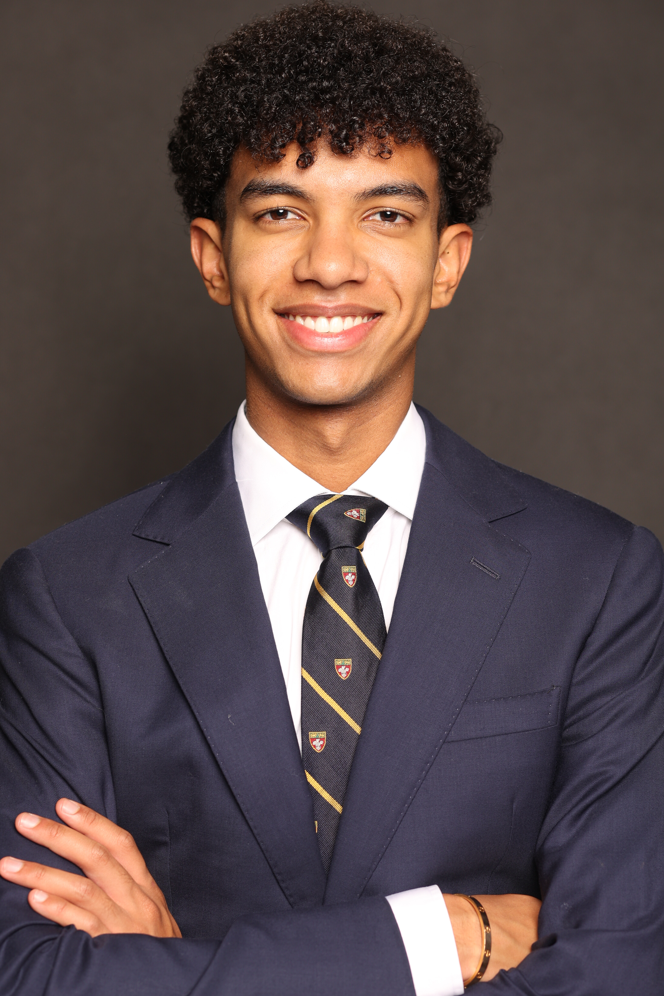 Smiling young man in a suit, arms crossed