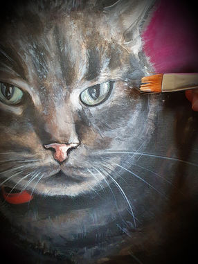 Dipinto di un gatto grigio con gli occhi verdi, con un pennello che lo colora