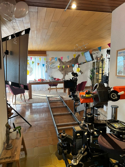 Préparation tournage vidéo fête anniversaire décorée : caméra, rails, ballons, « 21 »