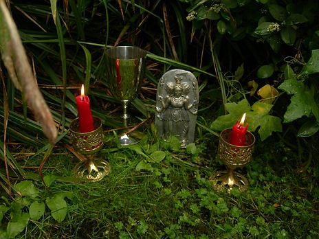 Grassy altar with red candles, a goblet and an icon for Hekate