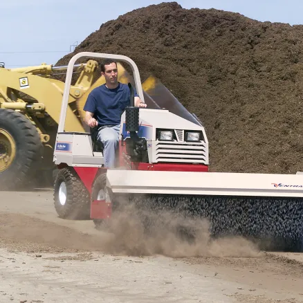 Ventrac with broom in a dusty place.