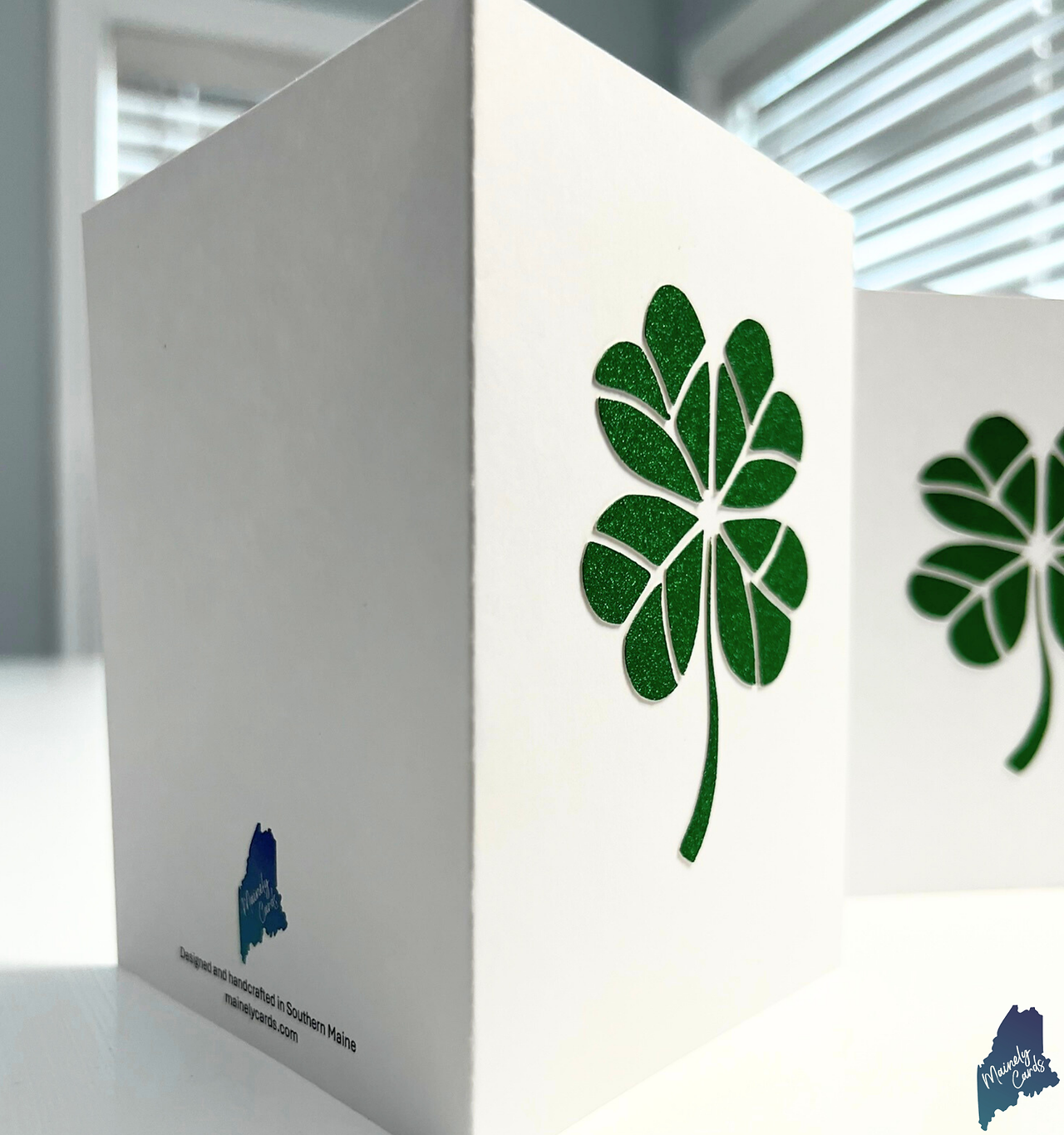 Side view of handcrafted four-leaf clover greeting cards highlighting the layered paper art and dimensional construction.