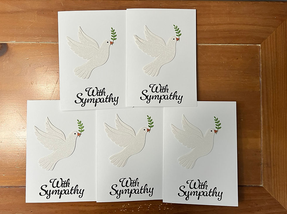 Five handmade sympathy cards arranged on a wooden surface, each featuring a white dove holding a green olive branch and the printed message “With Sympathy.”