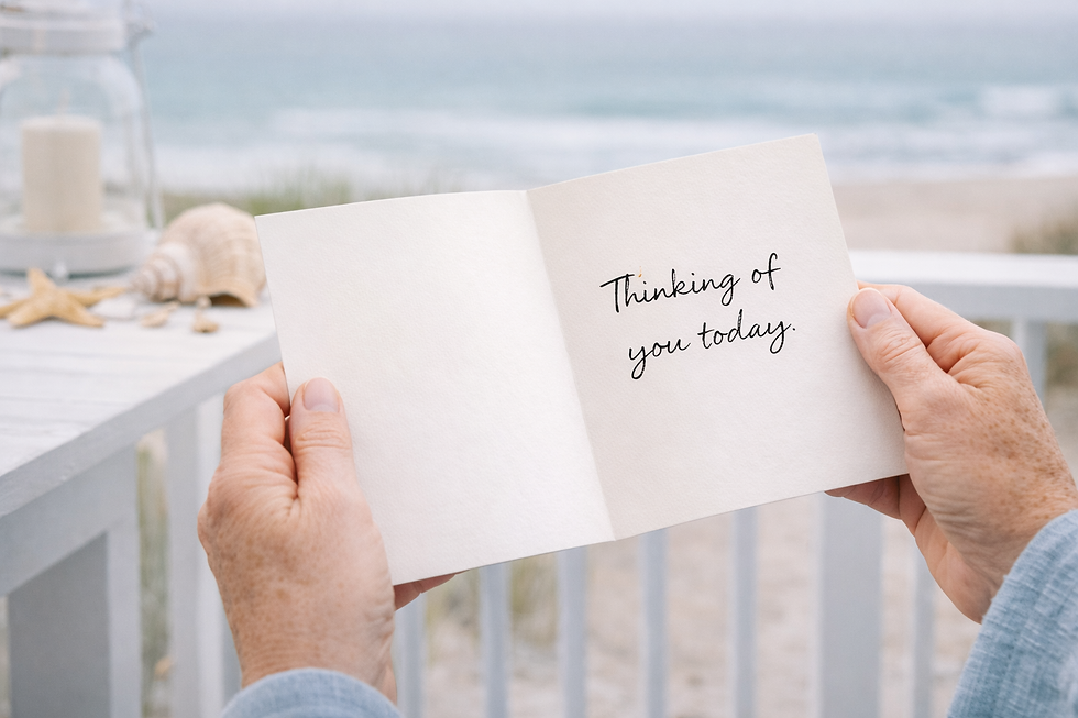 An older pair of hands holding an open folded greeting card that reads “Thinking of you today,” photographed in a bright coastal setting