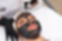 Cosmetologist applying black mask on the face of a beautiful woman for carbon peel.jpg