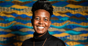 mulher negra com cabelo crespo curto sorrindo pra câmera